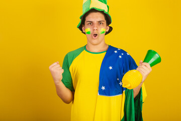 Young Brazilian man soccer fan. dressed in green, partying with brazil flag.