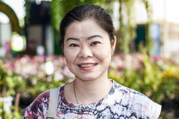 Asian cute 40s woman doing sightseeing  and smile happily, looking to camera in the  park in the morning. Selective focus at face. Happy woman concept.