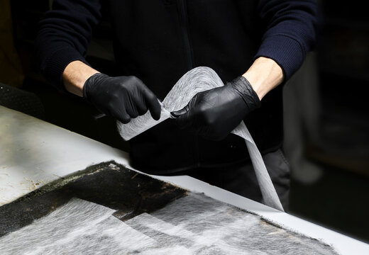 Installation of fiberglass: worker manually makes a component in glass fiber for automotive use. Creation of an object in composite material using his hands