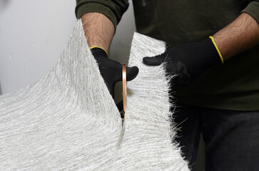Fiberglass sheets in various sizes are cut with scissors for the creation of industrial composite...
