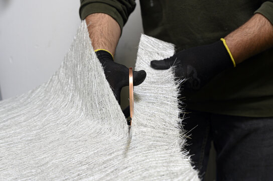 Fiberglass sheets in various sizes are cut with scissors for the creation of industrial composite material