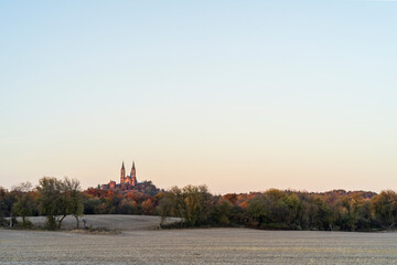 Fototapeta premium a landscape image of a basilica surrounded by colorful trees illuminated by the autumn sun in the fall