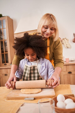 Mother teaching and cooking together with her daughter while kneading dough and doing bakery