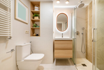 Designer bathroom with white porcelain sink, wooden chest of drawers, oblong mirror and matching shelves
