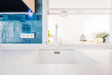 Kitchen nook with white stone countertop with integrated sink and glossy cobalt blue tiles