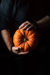 Photo on a black background an orange pumpkin in his hands