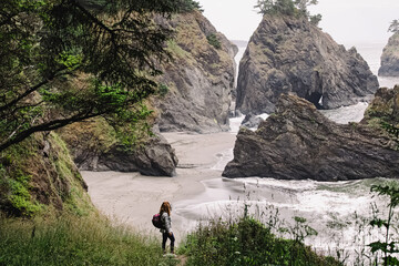 Woman standing with a view to a secret beach in Oregon coast. Hiking at the Pacific Northwest