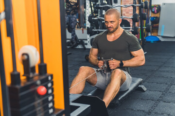 Fototapeta na wymiar Full-length indoor shot of extremely focused caucasian muscular bald male bodybuilder exercising at gym in dark t-shirt and gray shorts. High quality photo