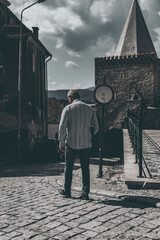 man walking by the street of the old town, view from behind