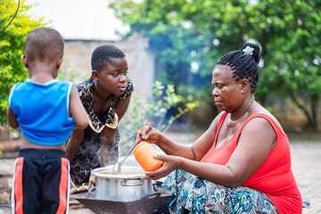 image of african woman and two kids in local kitchen outside- cooking tips concept