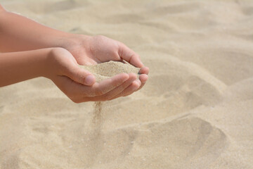 Fototapeta na wymiar Child pouring sand from hands on beach, closeup with space for text. Fleeting time concept
