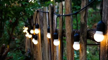 Small light bulbs decorated on wooden fence in local restaurant                               