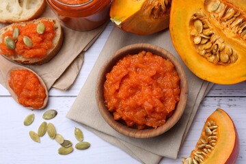 Delicious pumpkin jam and fresh pumpkin on white wooden table, flat lay