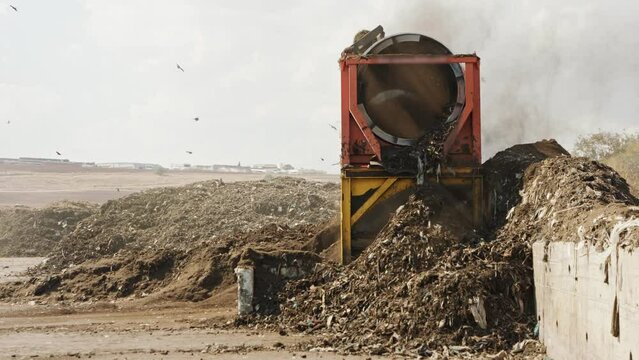 Industrial compost production site. Large rotary compost screening machine filtering compost