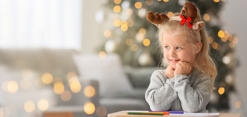 Happy little girl writing letter to Santa at home