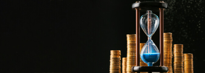 Hourglass and coins on black background with space for text. Time is money