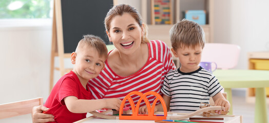 Nanny with cute little children playing at home