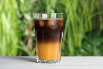 Tasty refreshing drink with coffee and orange juice on white table against blurred background