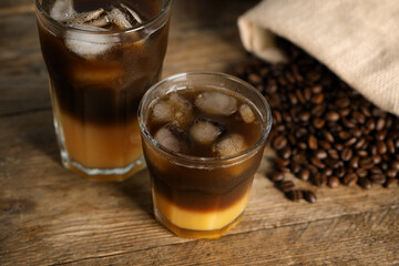 Tasty refreshing drink with coffee and orange juice on wooden table