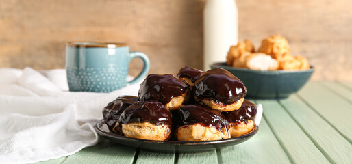 Plate with tasty profiteroles on color wooden table
