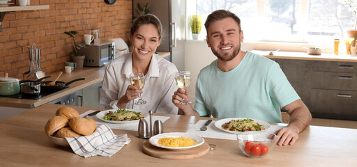 Happy young couple having lunch in kitchen