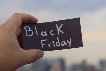 Hand holding a sign with the words black friday outdoors