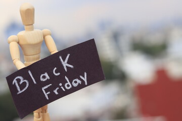 Wooden doll holding a sign with the words black friday outdoors
