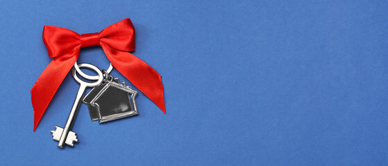 Key from new house with ribbon bow on blue background with space for text. Concept of real estate
