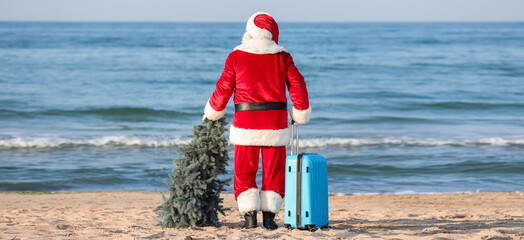Santa Claus with suitcase and Christmas tree at sea resort