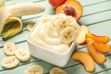 Bowl of tasty vanilla pudding with banana on color wooden table, closeup
