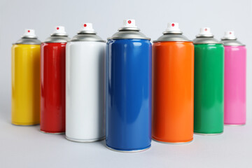 Colorful cans of spray paints on light grey background