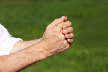 Man praying outdoors on sunny day, closeup