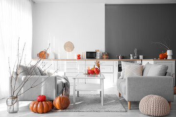 Interior of light kitchen with pumpkins, sofas and table