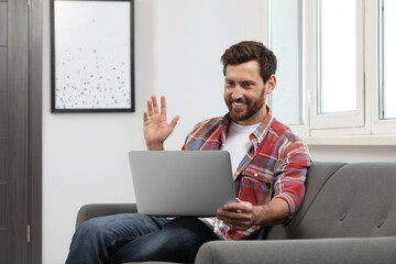 Happy bearded man having video chat on laptop at home