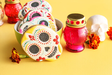 Bowl with cookies, flowers and candle on yellow background. El Dia de Muertos