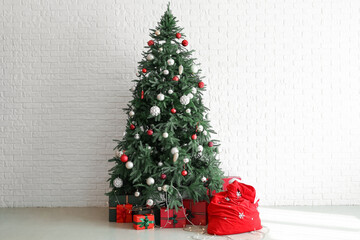 Santa bag with presents and Christmas tree near white brick wall