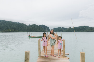 Fototapeta premium My Traveler family on wooden bridge in the sea and mountain at Nakhon si thammarat Thailand