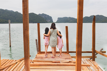 Obraz premium My Traveler family on wooden bridge in the sea and mountain at Nakhon si thammarat Thailand