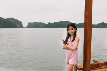 Obraz premium litte girl on wooden bridge in the sea and mountain at Nakhon si thammarat Thailand
