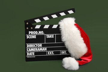 Movie clapper with Santa hat on green background