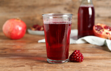 Glass of fresh pomegranate juice on wooden table