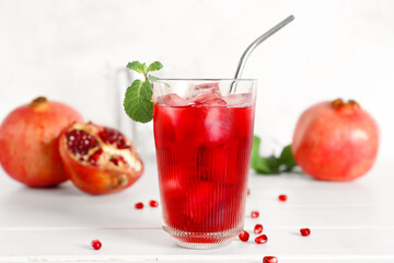 Glass of cold pomegranate juice on light wooden background