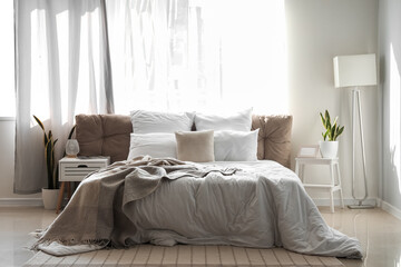 Interior of light bedroom with bedside table, stepladder and lamps