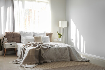 Interior of light bedroom with bedside table, stepladder and lamps