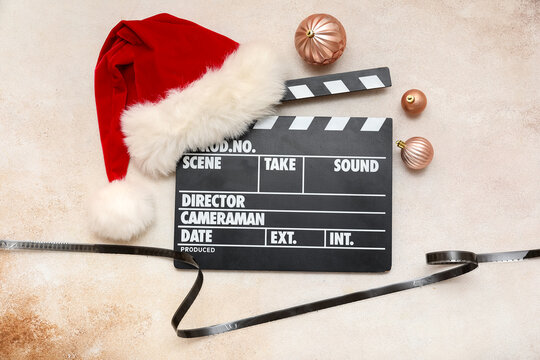 Movie clapper with Santa hat, Christmas balls and film reel on grunge background