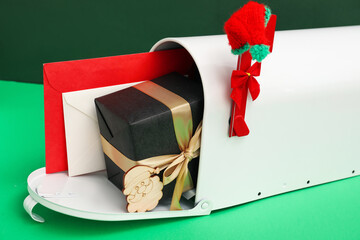 Mailbox with letters to Santa, Christmas gift and hat on green background, closeup
