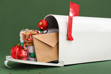 Mailbox with letters to Santa, presents, cookies and Christmas balls on green background, closeup