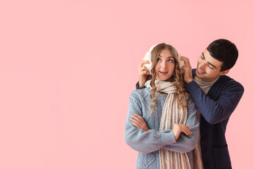 Fototapeta premium Loving couple in warm clothes on pink background
