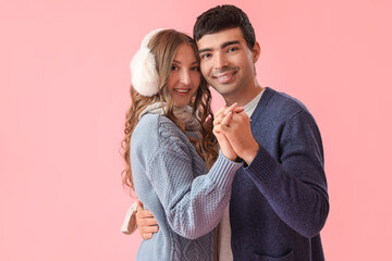 Naklejka premium Loving couple in warm clothes holding hands on pink background