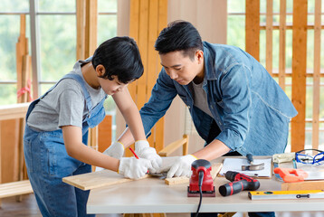 Asian cheerful male dad son carpenter woodworker colleague in jeans outfit with safety gloves...
